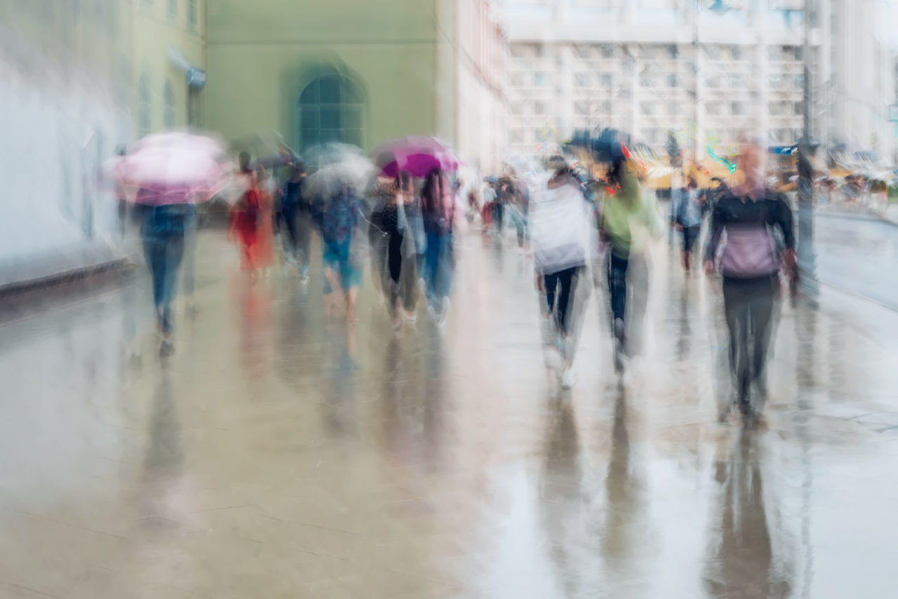 GROUP OF PEOPLE WALKING ON WET ROAD