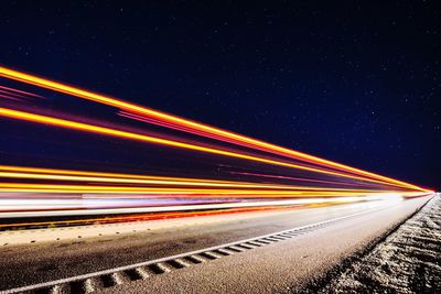 Light trails on road against clear sky at night