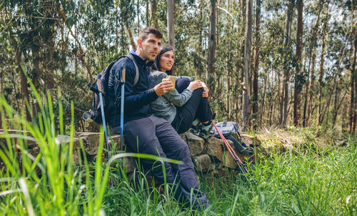 Young couple sitting on land in forest