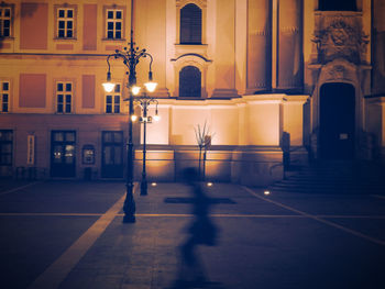 Illuminated street light by building at night