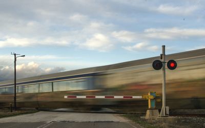 Blurred motion of train by railroad crossing against sky