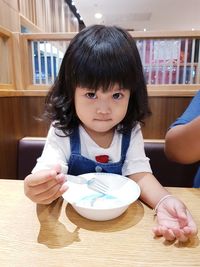 Portrait of cute girl sitting at table in restaurant