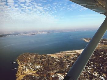 Aerial view of city by sea against sky