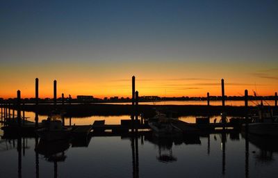 Silhouette of wooden post in lake against sky during sunset