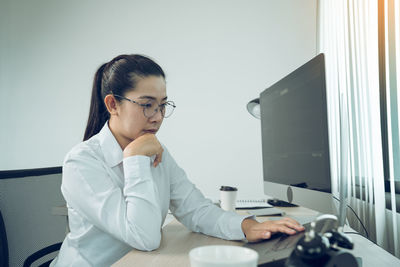 Young woman using phone while sitting on table