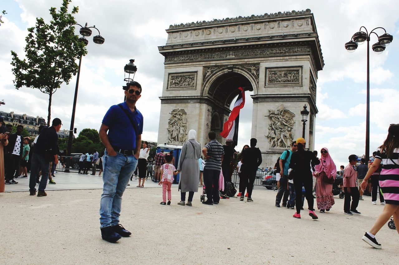 large group of people, architecture, built structure, sky, real people, cloud - sky, travel destinations, day, triumphal arch, patriotism, outdoors, women, flag, men, lifestyles, city, building exterior, crowd, adult, people