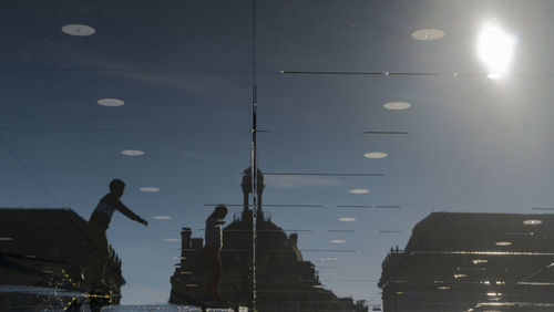Low angle view of silhouette man standing by illuminated buildings against sky