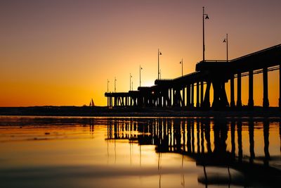 Silhouette pier over sea against sky during sunset