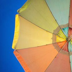 Low angle view of colorful umbrella against clear blue sky