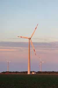 Windmills on field against clear sky