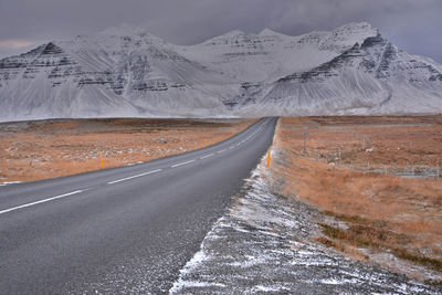 Road by snowcapped mountain against sky