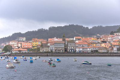 Coastal village in the background and fishing boats in the sea in the foreground. galicia, spain