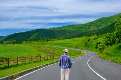 Rear view of man walking on road against mountain
