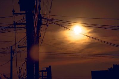 Low angle view of silhouette electricity pylon against sky during sunset