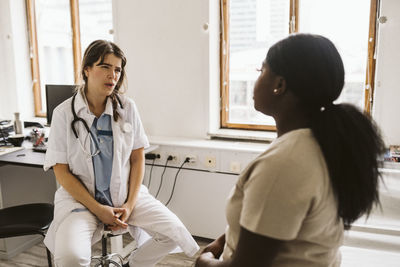 Female doctor discussing with patient while consulting in medical clinic