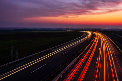 High angle view of light trails on road against sky at sunset