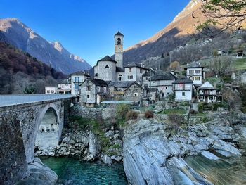 Arch bridge over river amidst buildings against sky