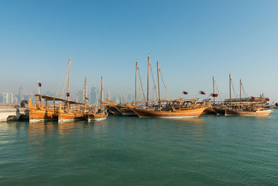 Boats moored in sea against clear blue sky