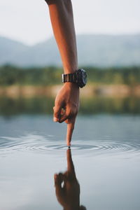 Low section of woman legs on water against sky