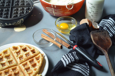 Waffle, waffle iron, cinnamon sticks, utensils and ingredients