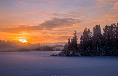 Scenic view of snow covered landscape at sunset
