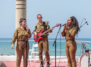 People standing by sea against clear sky