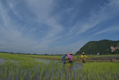 People on agricultural field against sky