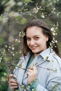 Portrait of a beautiful smiling joyful girl in cherry blossoms in spring