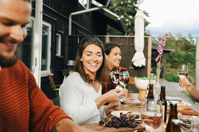 Smiling woman looking at friend while enjoying during dinner in party