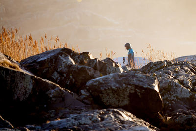 Rear view of man standing on rock by sea