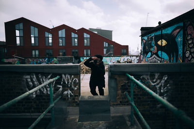 Man standing on staircase in city against sky