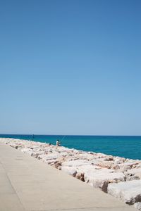 Scenic view of beach against clear blue sky