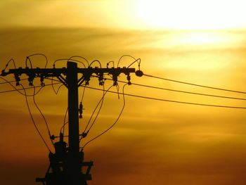 Low angle view of silhouette electricity pylon against sky during sunset