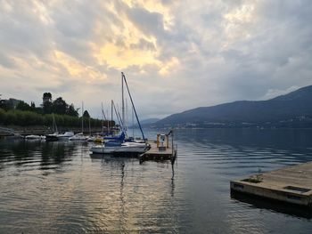 Sailboats moored in lake against sky during sunset