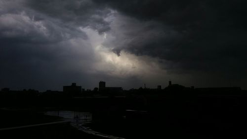 Silhouette of city against cloudy sky