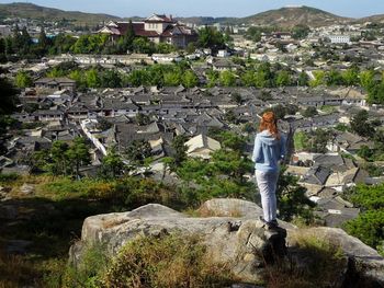 Full length of woman overlooking townscape while standing on rock