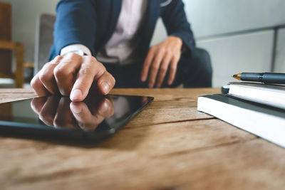 Midsection of businessman using digital tablet at desk