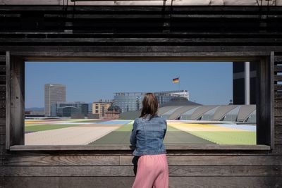 Rear view of woman standing against buildings in city