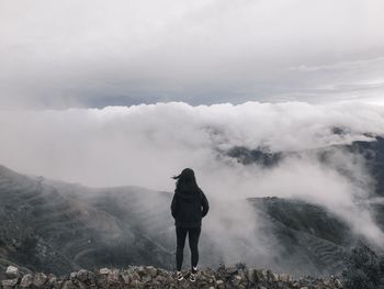 Rear view of man standing on mountain against sky