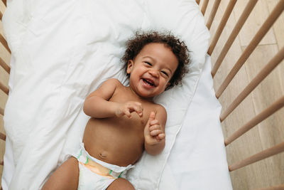 High angle portrait of smiling woman lying on bed