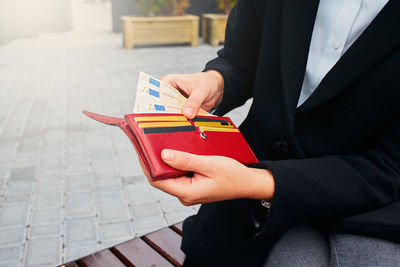 Midsection of woman holding red while sitting outdoors