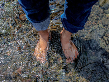 Low section of man standing by stream