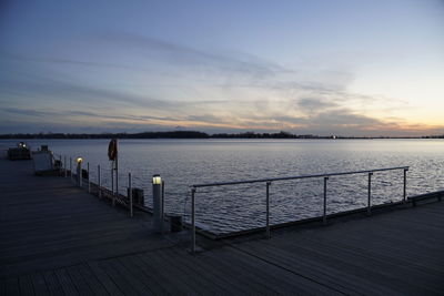 Pier on sea against sky during sunset