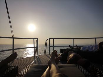 Low section of people relaxing in swimming pool against sky