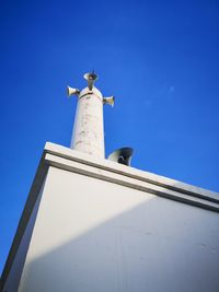 Low angle view of seagull on building against blue sky