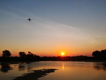 Scenic view of silhouette plane against sky during sunset