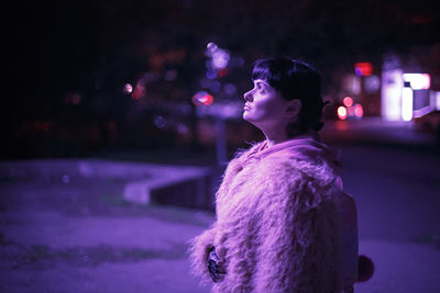 Rear view of woman looking at illuminated city at night