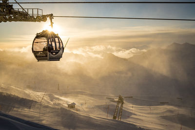 Overhead cable car on mountain against sky during sunset