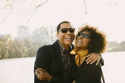 Happy couple standing by river against clear sky in city