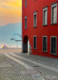 Street by building against sky during sunset